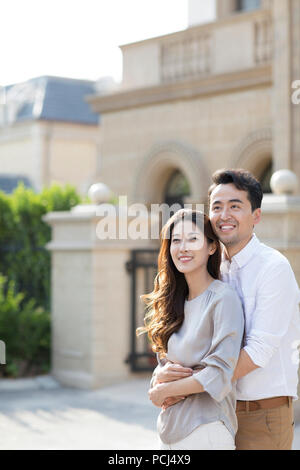 Fröhliche junge chinesische Paar umarmen vor Ihrer Villa Stockfoto