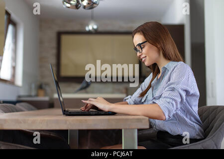 Glückliche junge Frau mit Laptop zu Hause kommunizieren, lächelnd Stockfoto