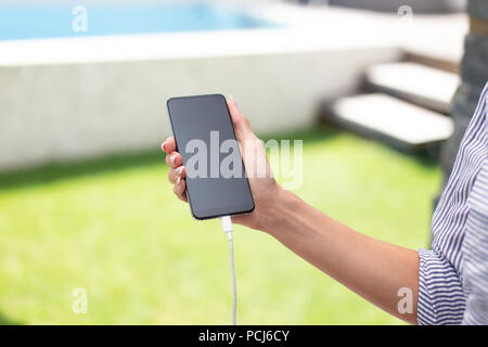 Frau hand Smartphone während des Ladevorgangs closeup Stockfoto