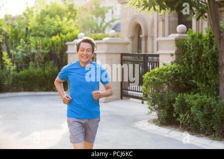 Fröhlicher älterer Chinesischer Mann joggen außerhalb Stockfoto