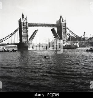 1960er Jahre, ein Boot unter einem offenen Tower Bridge, London, England, UK. Ein Wahrzeichen von London, die Brücke wurde offiziell im Jahr 1894 von der Prinz von Wales eröffnet. Stockfoto