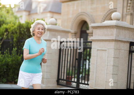 Freundliche ältere chinesische Frau joggen außerhalb Stockfoto