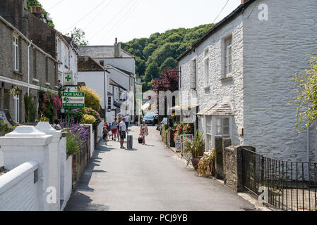 Urlauber zu Fuß in einer engen Straße in urigen Hütten in Polperro, Cornwall, England, Großbritannien Stockfoto