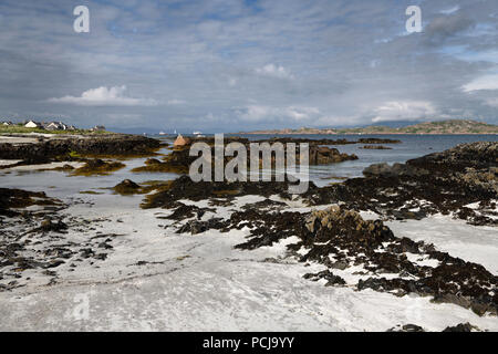 Weißer Sand und Felsen am Ufer des Isle of Iona mit Mull auf der anderen Seite der Sound von Iona Inneren Hebriden Schottland Großbritannien Stockfoto