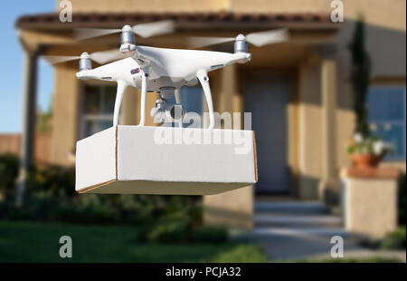 Unbemannte Luftfahrzeuge (UAV) Quadcopter Drohne liefern Paket am Haus. Stockfoto