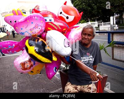 ANTIPOLO CITY, Philippinen - Juli 30, 2018: Ein Mann verkauft sortiert Spielzeug Ballons außerhalb des beliebten Reiseziel Unsere Liebe Frau des Friedens und gute Vo Stockfoto