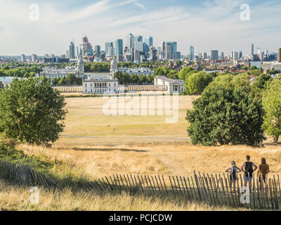 Blick von Greenwich Park Richtung Universität (Old Royal Naval College) mit der Themse und den Wolkenkratzern der Canary Wharf. Stockfoto