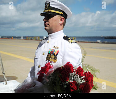 NORFOLK, Virginia (Aug. 1, 2018) ein Navy Officer hält Blumen, während das U-Boot Squadron 6 Ändern des Befehls an Bord der Virginia zu einem Familienmitglied vorgestellt werden - Klasse Angriffs-U-Boot USS Washington (SSN787) in Norfolk, Virginia. Kapitän Martin Muckian entlastet Kapitän Carl Hartsfield als Kommandant, Submarine Squadron Six. (U.S. Marine Foto von Chief Mass Communication Manager Darryl Holz/Freigegeben) Stockfoto