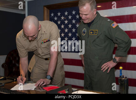 NEWPORT NEWS, Virginia (Aug. 1, 2018) Lt. j.g. Zachary Klassen, von Phoenix, auf USS Gerald R. Ford's (CVN 78) Waffen Abteilung zugewiesen, Zeichen seiner Lieferung der ständigen Termin Schreibarbeit während der Werbeaktion Zeremonie an Bord Ford. (U.S. Marine Foto von Mass Communication Specialist 2. Klasse Katze Campbell) Stockfoto