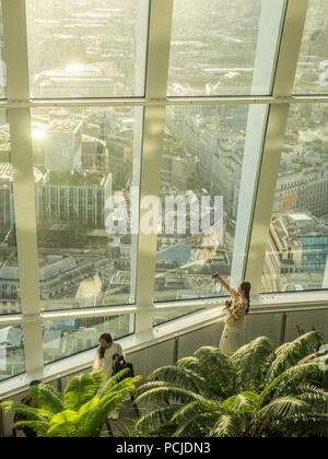 Lady nimmt ein Selfie, während Licht in den Sky Garden im 'Walkie-Talkie' Skyscraper, London, England, strömt. Stockfoto