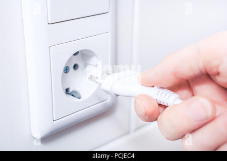Weibliche Hand und Verbinden von elektrischen Stecker in eine Steckdose Stockfoto