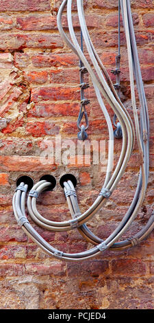 Externe elektrische Leitungen- und Telefonkabel fest auf eine Mauer, die für die Verteilung von Strom Stockfoto