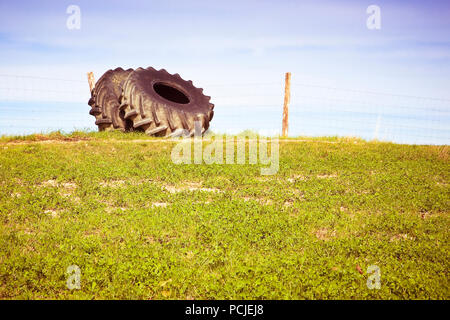 Alte abgebaut werden paar Reifen eines großen Traktor in einem Land, Road-getonten Bild Stockfoto