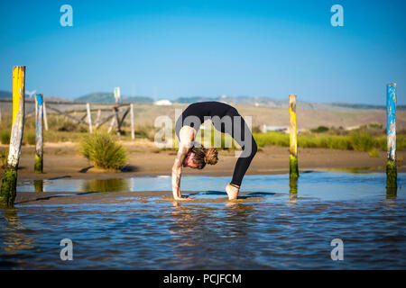 Frau am Strand Los Lances, ein Rad yoga Pose, Tarifa, Cadiz, Andalusien, Spanien Stockfoto