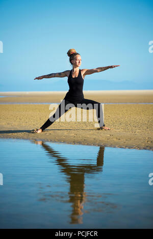 Frau am Strand Los Lances, Krieger II yoga Pose, Tarifa, Cadiz, Andalusien, Spanien Stockfoto