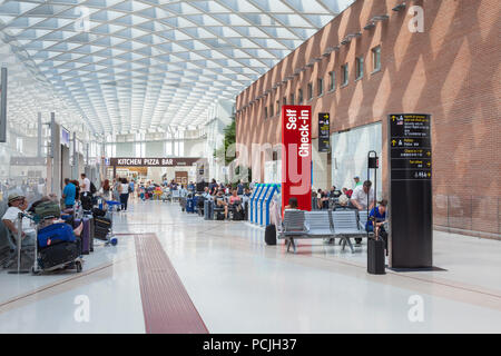 Passagiere am Flughafen Marco Polo in Venedig, Venedig, Venetien, Italien sitzen warten nach der Prüfung s in um das Selbst in Maschinen prüfen Stockfoto