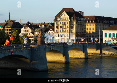 Die mittlere Brücke in Basel - eine der ältesten Überquerung des Rheins (Rhein) in der Abenddämmerung. Menschen zu Fuß über die Brücke, mit einem stadtbild in der Stockfoto