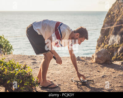 Portrait von jungen männlichen einstellen und die Drohne weg auf die Landschaft Berg in der Nähe des Ozeans zu nehmen Stockfoto