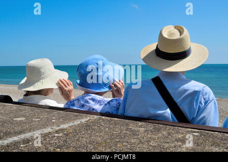 Menschen tragen Sommer Hüte an einem windigen Tag am Strand Stockfoto