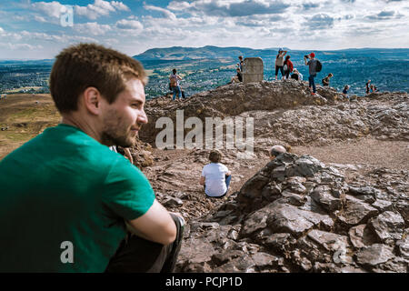 Wanderer auf Arthur's Seat peak in Holyrood Park mit Pentland Hills Regional Park im Hintergrund. Edinburgh, Schottland, Vereinigtes Königreich. Stockfoto