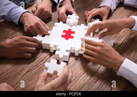 Erhöhten Blick auf Geschäftsleute Lösung Puzzle über Holz- Hintergrund Stockfoto