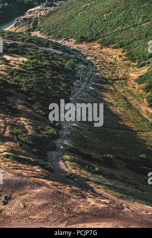 Wanderer auf dem Weg in Holyrood Park, Salisbury Craigs und Arthur's Seat bei Sonnenuntergang. Edinburgh, Schottland, Vereinigtes Königreich. Stockfoto