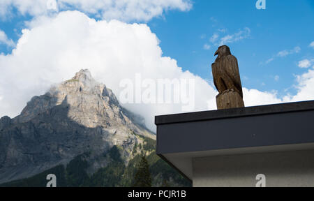 Hölzerne Adler Skulptur in der Schweiz mit einem Berg (Dündenhorn) im Hintergrund Stockfoto