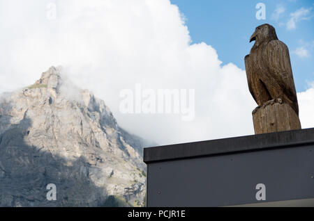 Hölzerne Adler Skulptur in der Schweiz mit einem Berg (Dündenhorn) im Hintergrund Stockfoto