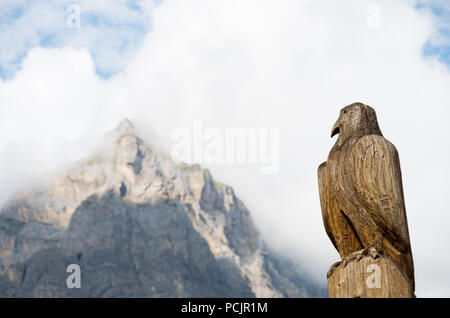 Hölzerne Adler Skulptur in der Schweiz mit einem Berg (Dündenhorn) im Hintergrund Stockfoto