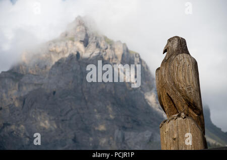 Hölzerne Adler Skulptur in der Schweiz mit einem Berg (Dündenhorn) im Hintergrund Stockfoto