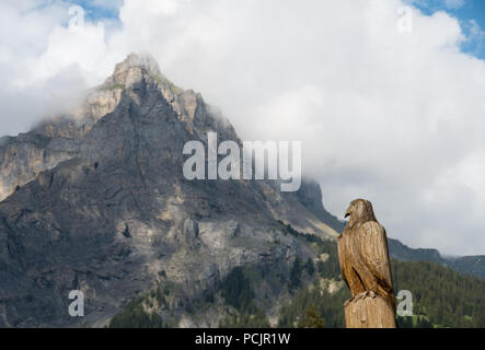 Hölzerne Adler Skulptur in der Schweiz mit einem Berg (Dündenhorn) im Hintergrund Stockfoto