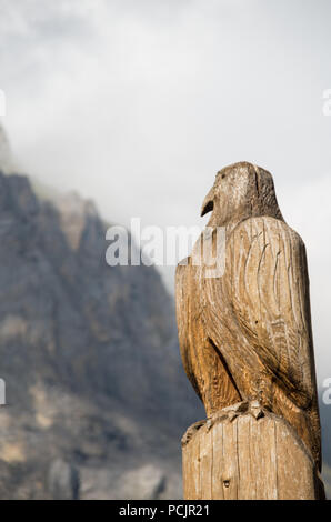 Hölzerne Adler Skulptur in der Schweiz mit einem Berg (Dündenhorn) im Hintergrund Stockfoto