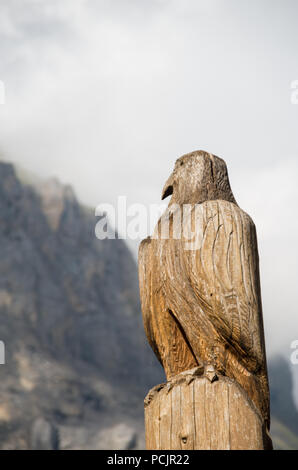 Hölzerne Adler Skulptur in der Schweiz mit einem Berg (Dündenhorn) im Hintergrund Stockfoto