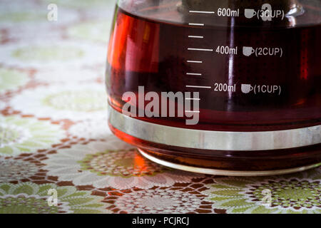 Ein Glas Teekanne mit Tee Blätter steht auf dem Küchentisch. Stockfoto