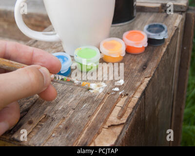Künstler Hand versuchen, Farben mit Pinsel auf einer hölzernen Oberfläche Stockfoto