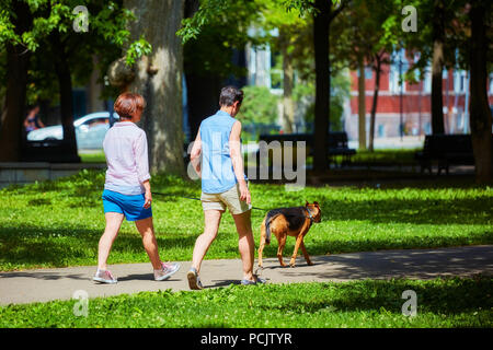 Zwei Frauen gehen in den Park mit einem Hund an einem sonnigen Tag. Park La Fontaine, Montreal, Kanada. Stockfoto