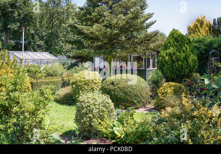 Zaandam, Niederlande, 2. Juli 2018: Gartenhaus und Gewächshaus von einem hübschen Garten umgeben in den Niederlanden Stockfoto