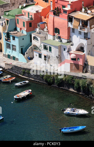 Fischerboote und der Promenade in Corricella auf Procida, Italien, mit den lebhaft bunten Häuser in verschiedenen Pastelltönen lackiert Stockfoto