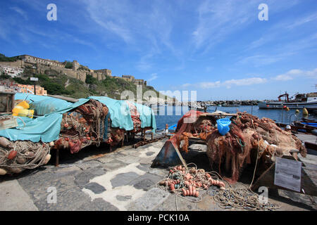 Racks der Fischernetze an der Promenade von Corricella auf Procida, Golfo di Napoli, Italien, mit dem ehemaligen Gefängnis Terra Murata im Hintergrund Stockfoto