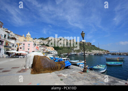 Fischerboote und der Promenade in Corricella auf Procida, Italien, mit den lebhaft bunten Häuser in verschiedenen Pastelltönen lackiert Stockfoto