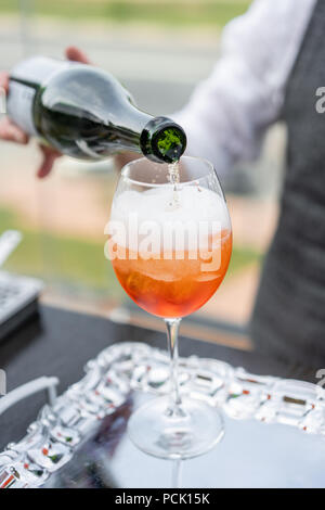 Der Barkeeper macht cocktail Aperol Spritz. Glas, selektiven Fokus besprühen. Alkoholische Getränk auf Theke mit Eiswürfeln und Orangen. Party im Freien Stockfoto