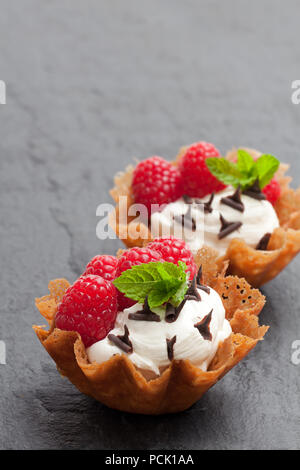 Brandy snap Körbe mit Eis und Beeren auf schwarzen Stein Hintergrund Stockfoto