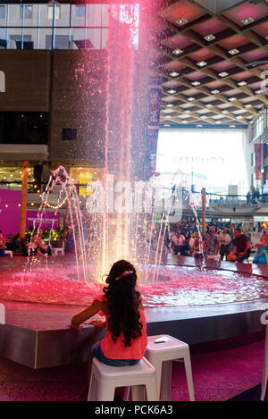 Ein junges Mädchen auf der Suche an einem grossen Brunnen in der Complexe Desjardins Einkaufszentrum in der Innenstadt von Montreal Stockfoto