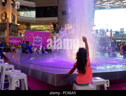 Ein junges Mädchen versucht, das Wasser in einem grossen Brunnen in der Complexe Desjardins Einkaufszentrum in der Innenstadt von Montreal zu berühren Stockfoto