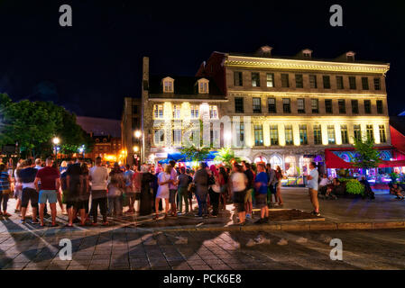 Nachtleben im Sommer auf Platz Jacques Cartier in Montreal's Old Port District - eine Gruppe von Menschen ein strassenmusikant zu hören Stockfoto