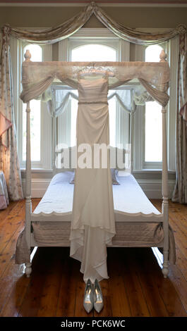 Wedding Dress legte auf Himmelbett vor der Hochzeit. Stockfoto