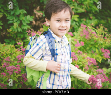 Young Boy hält EINEN Rucksack ist aufgeregt, um zurück zur Schule gehen Young Boy Holding EINEN Rucksack ist aufgeregt, um wieder zur Schule gehen Stockfoto