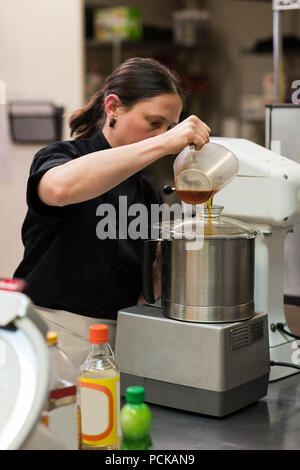 Koch gießen Speiseöl in einer Schleifmaschine Stockfoto