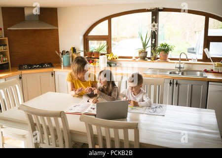 Mutter Kinder helfen bei den Hausaufgaben in der Küche Stockfoto