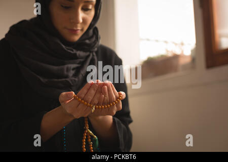 Muslimische Frau mit Gebet Perlen zu Hause beten Stockfoto